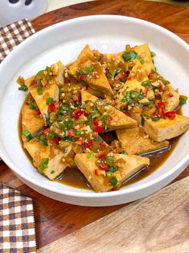 Braised tofu triangles with shallot, garlic, chilies and green onions in a savory sauce