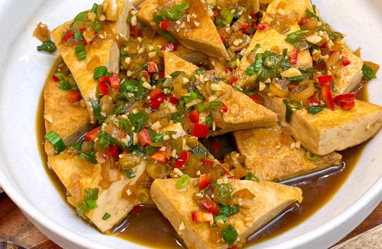 Braised tofu triangles with shallot, garlic, chilies and green onions in a savory sauce