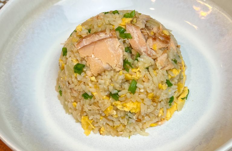 Garlic butter fried rice with smoked salmon, eggs, and scallions served in a white bowl
