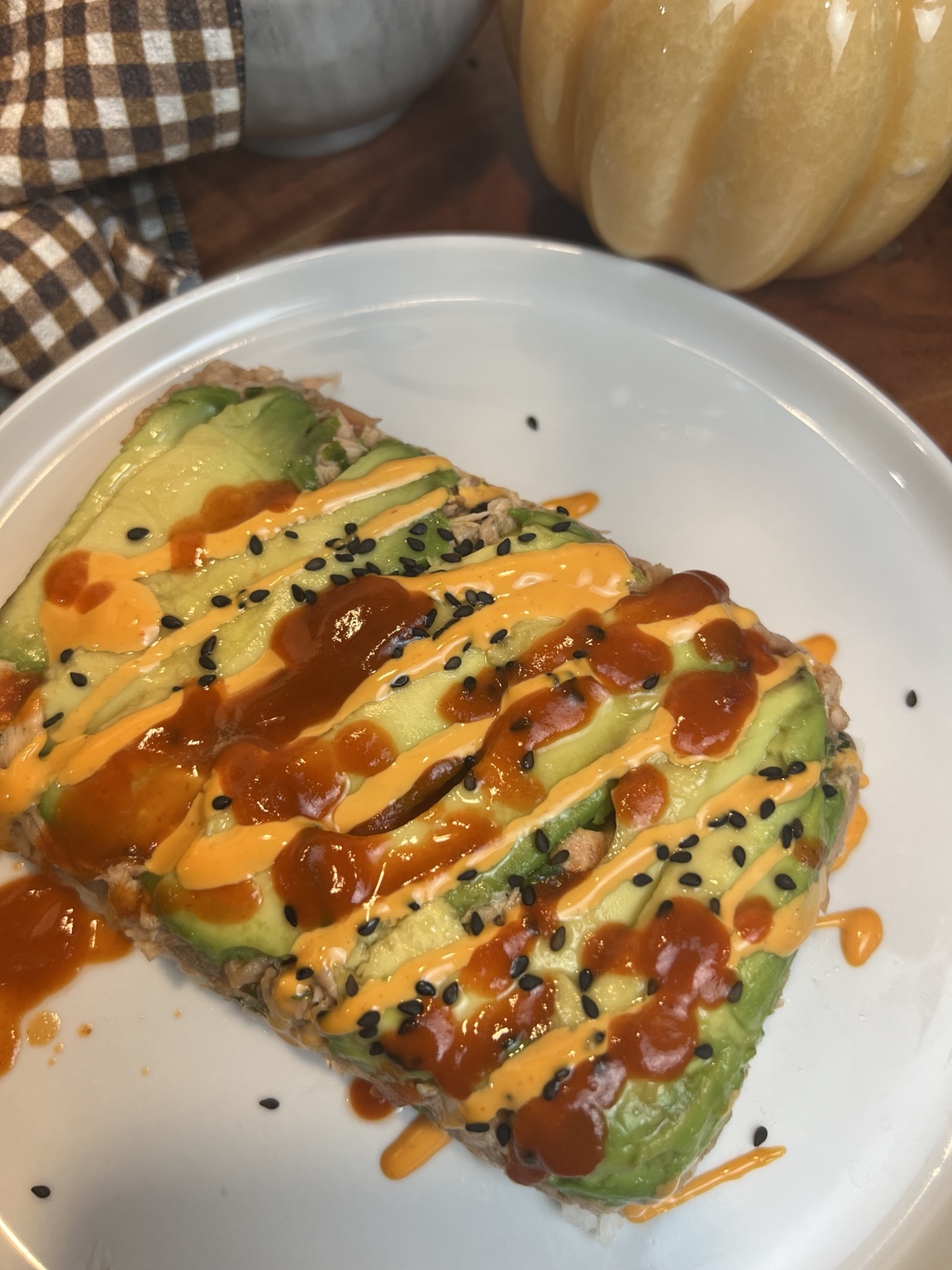 Air fryer salmon stack layered with avocado, seasoned salmon, and sushi rice, topped with spicy mayo and Sriracha.
