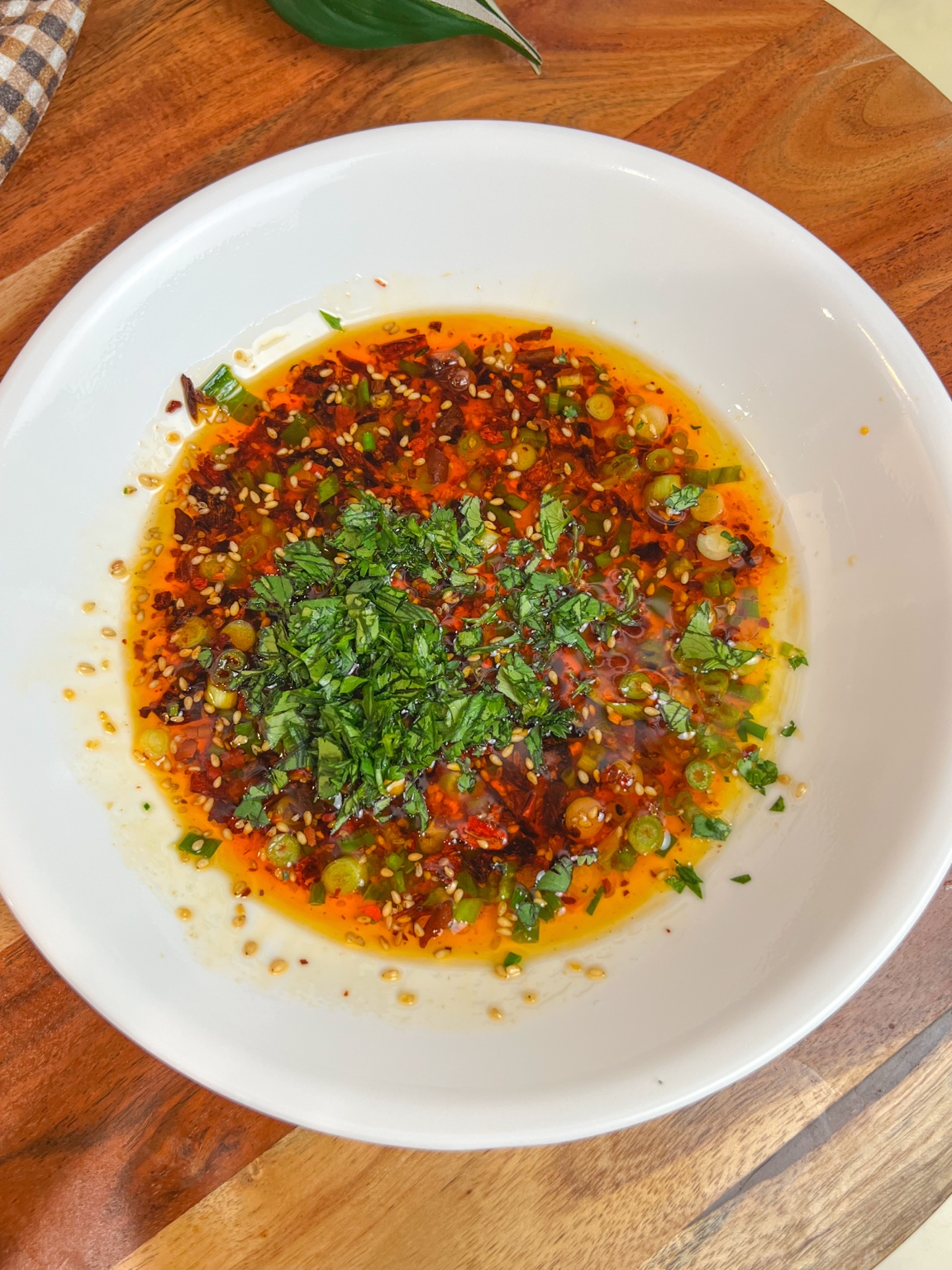 Chili crisp bread dipping oil with scallions, sesame seeds, and cilantro in a white bowl