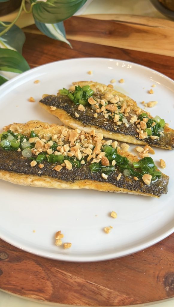 Pan-seared branzino fillets topped with scallion oil and crushed peanuts