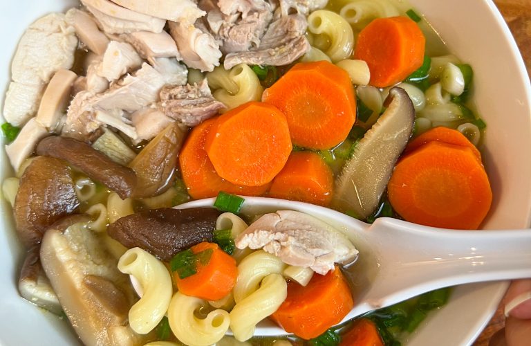 Vietnamese chicken macaroni soup with chicken, carrots, shiitake mushrooms, and green onions.